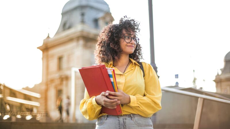 woman in yellow jacket holding books